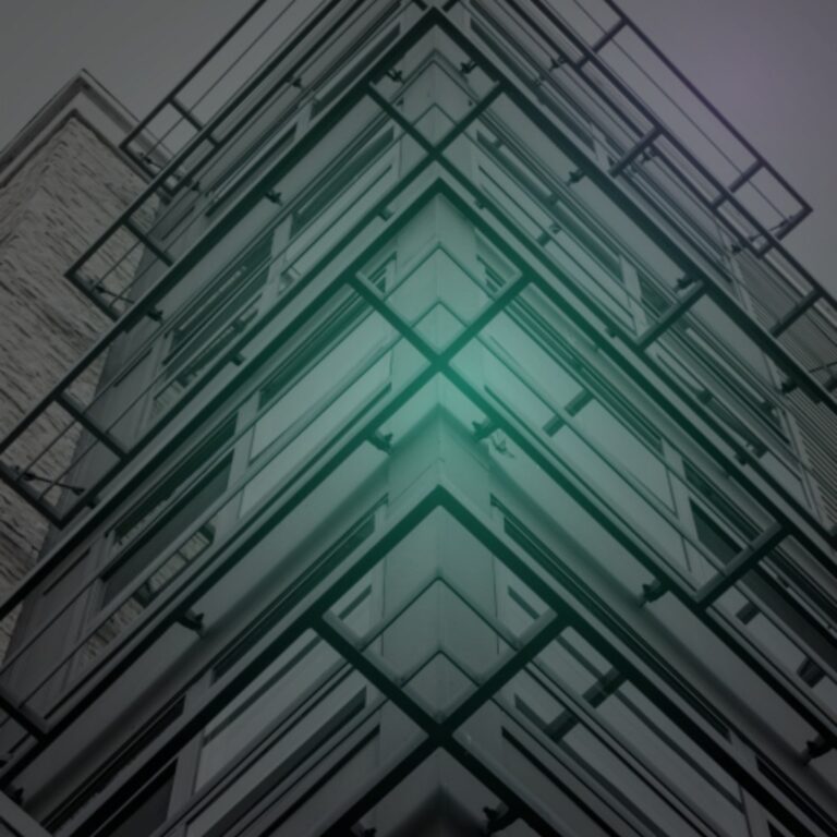 Upward view of a building corner in converging steel and glass, lit teal at the apex